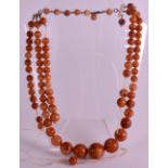 AN EARLY 20TH CENTURY CARVED AMBER TYPE NECKLACE of graduated form. 2Ft 2ins long overall.