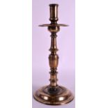 A 17TH CENTURY BRASS CANDLESTICK with ribbed body and circular foot. 11Ins high.