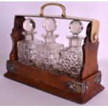 AN EDWARDIAN WALNUT MINIATURE TANTALUS with three cut glass bottles and stoppers. 9.25ins wide.