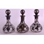 AN ART NOUVEAU SILVER OVERLAID SCENT BOTTLE AND STOPPER together with two others. 4.75ins high. (3)