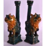 A PAIR OF LATE 19TH CENTURY SANCAI TYPE GLAZED CANDLESTICKS modelled as dogs of foe upon square