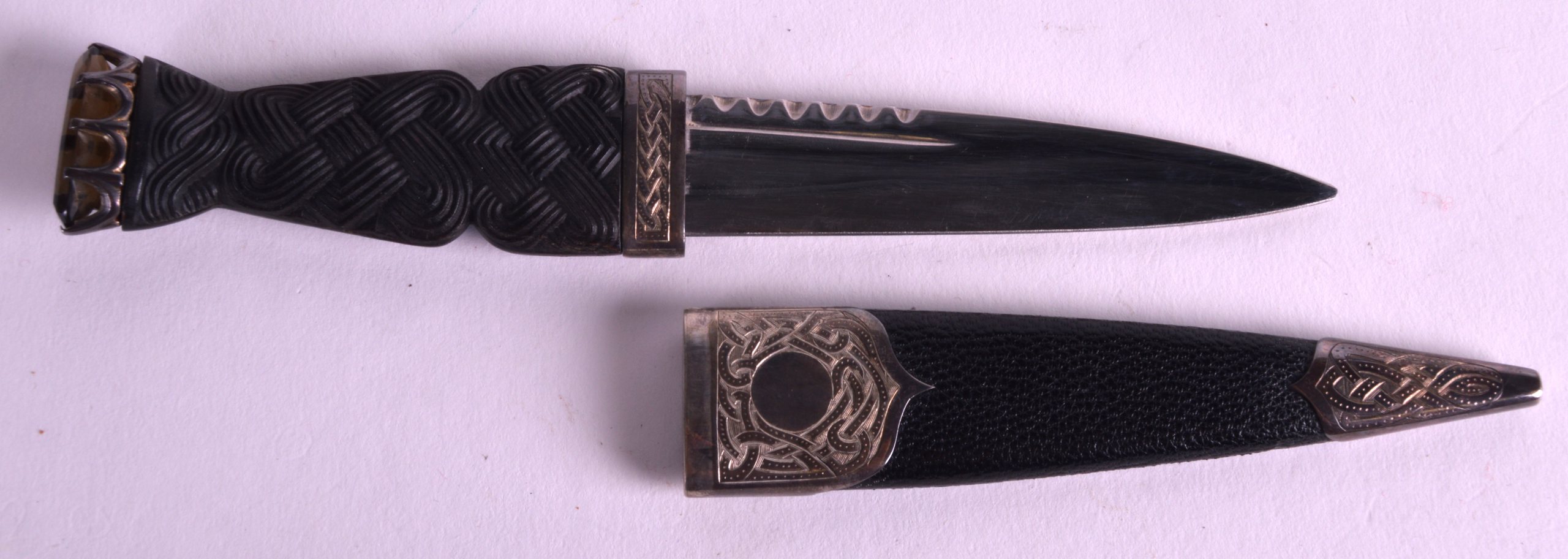 A SCOTTISH SILVER MOUNTED LEATHER CASED DAGGER the top inset with a smoky hardstone. 7.5ins long.