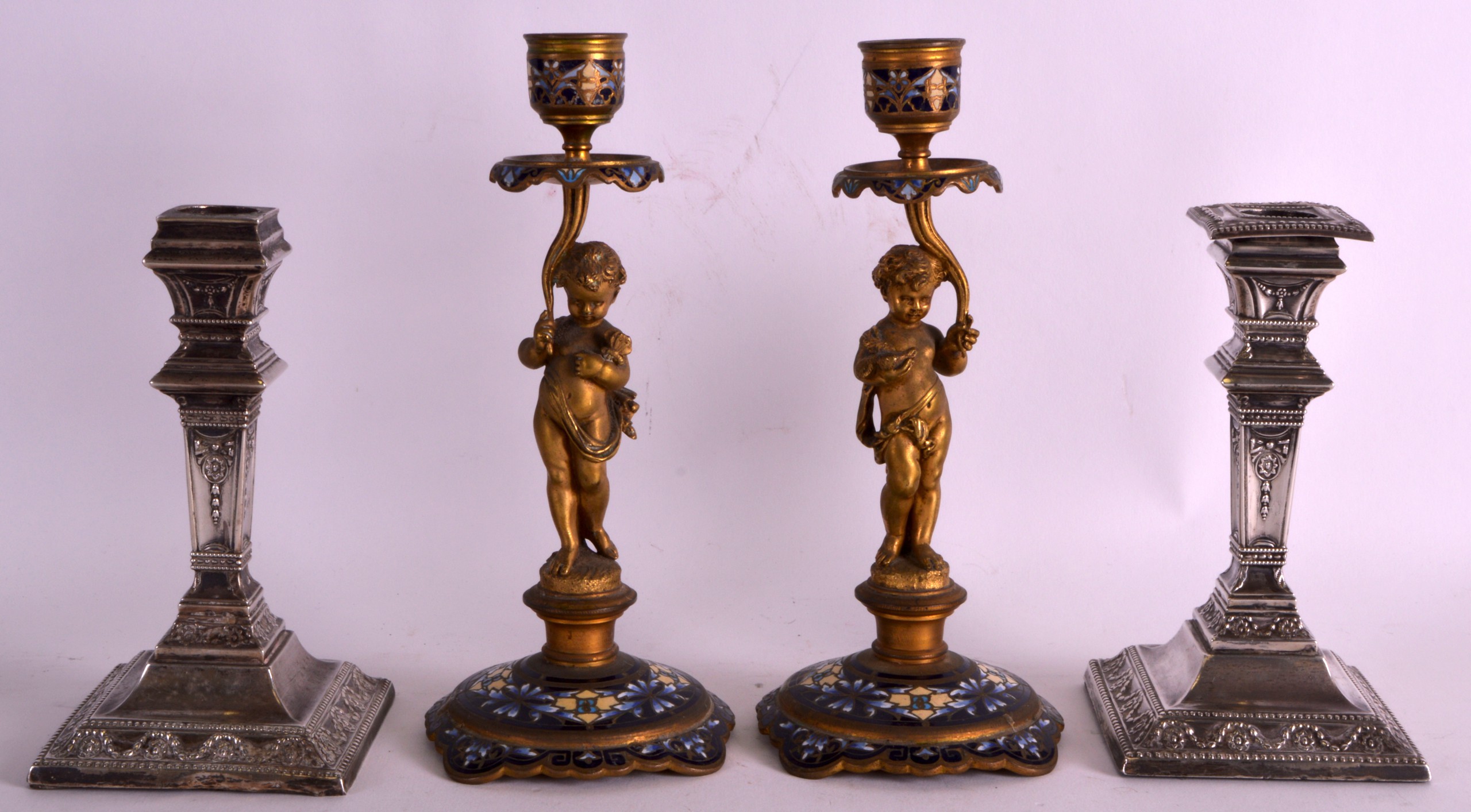 A PAIR OF EDWARDIAN SILVER BACHELOR CANDLESTICKS together with a smaller pair of French champlevé