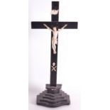 A 19TH CENTURY BONE AND CORPUS CHRISTI modelled upon a black painted crucifix. 1Ft 5ins high.