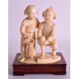 AN EARLY 20TH CENTURY CHINESE CARVED IVORY FIGURE OF TWO YOUNG CHILDREN modelled holding a basket,