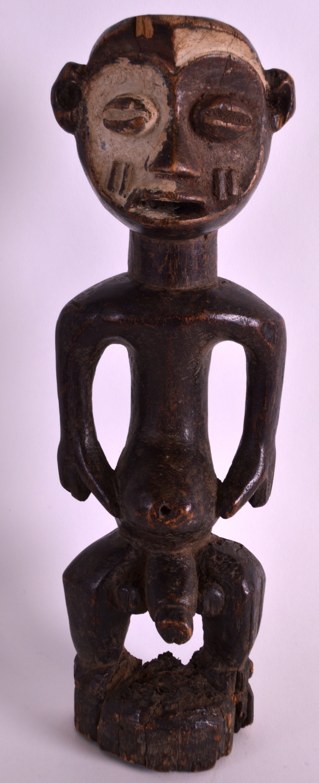 AN EARLY 20TH CENTURY AFRICAN CARVED HARDWOOD FERTILITY FIGURE modelled with exposed genitalia.