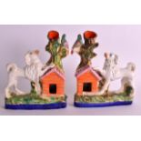 A PAIR OF STAFFORDSHIRE FIGURES OF POODLES modelled with one leg upon kennels. 7.5ins wide.