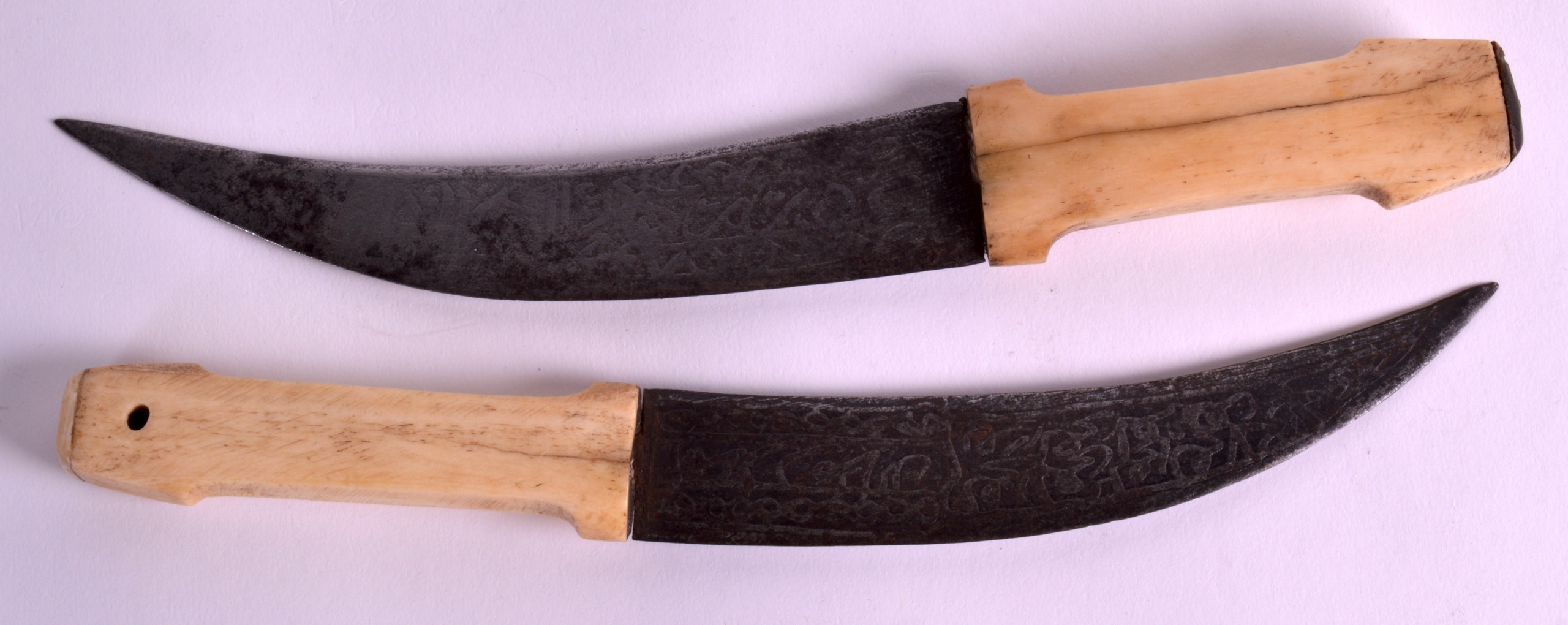 A PAIR OF 19TH CENTURY CARVED INDIAN BONE HANDLED DAGGERS each inscribed all over with scrolling