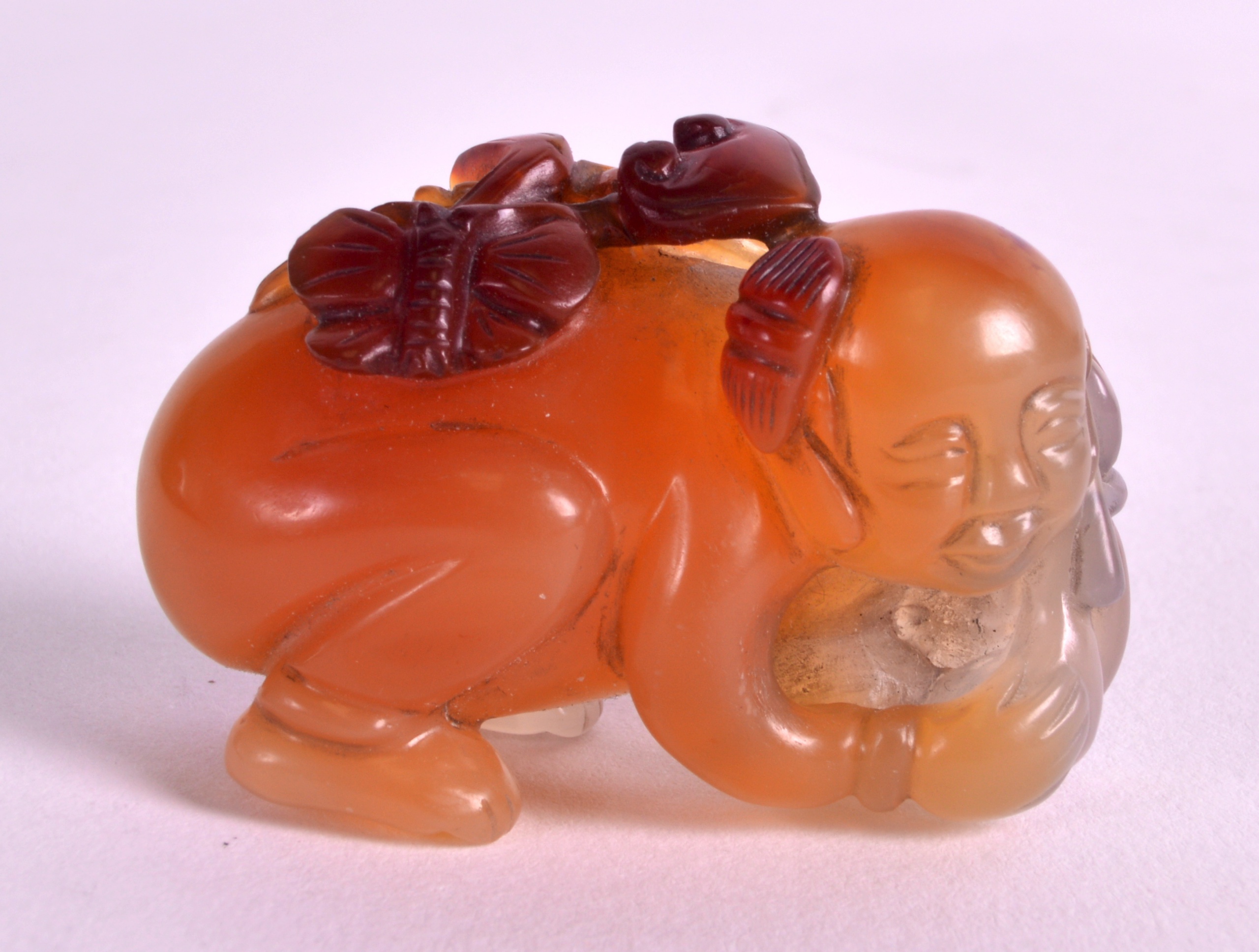 A CHINESE CARVED AGATE FIGURE OF A RECUMBANT CHILD modelled with a butterfly upon his back. 1.