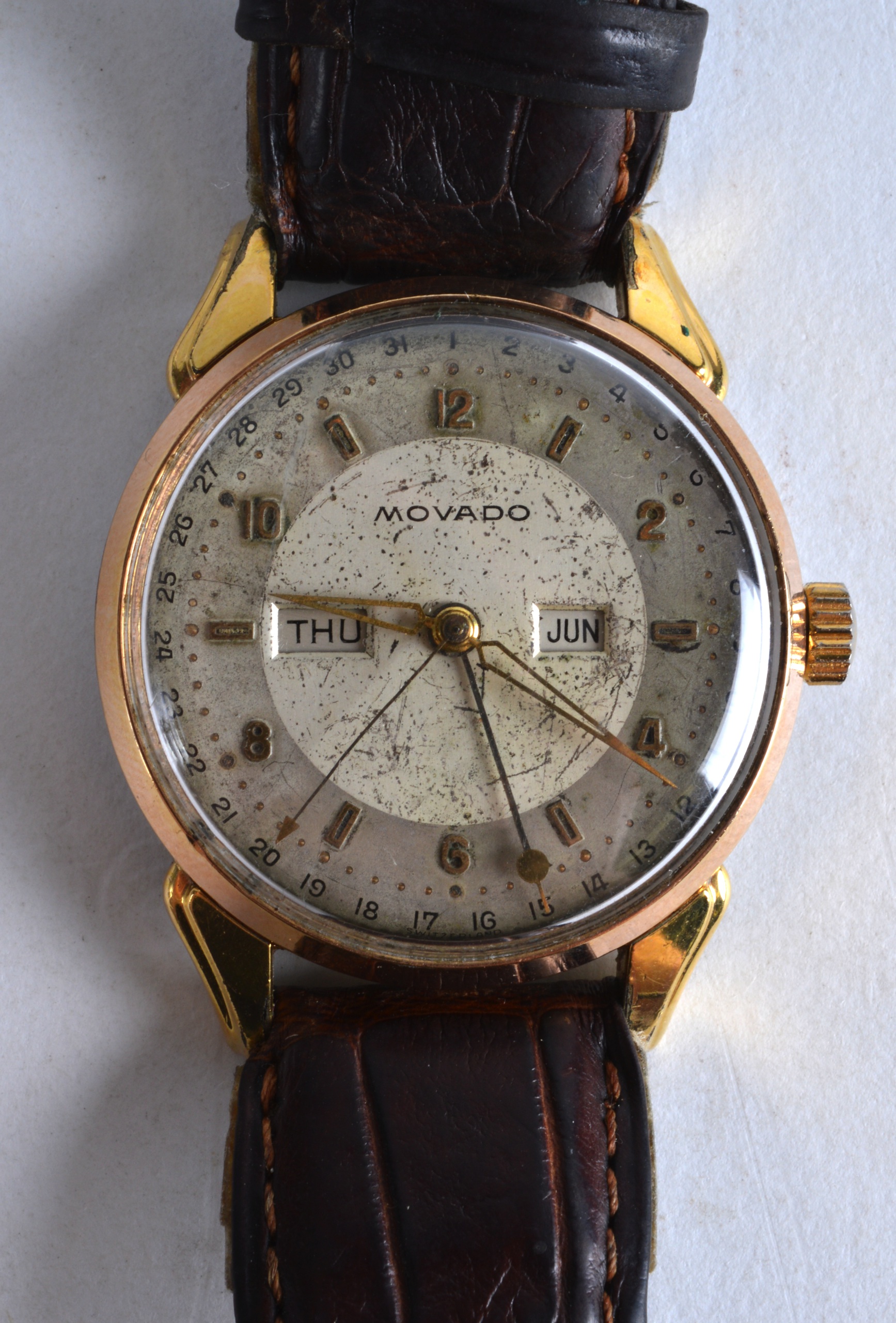 A 1950S GENTLEMANS MOVADO YELLOW METAL GENTLEMANS WRISTWATCH with brown leather strap. 1.5ins