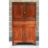 A REGENCY MAHOGANY CUPBOARD with associated top, twin panel doors upon a base with one drawer a pair