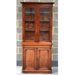 A VICTORIAN MAHOGANY BOOKCASE the upper section with adzed moulded doors, over a two door cupboard