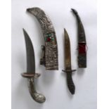 AN EARLY 20TH CENTURY TIBETAN WHITE METAL JEWELLED DAGGER together with another similar dagger.