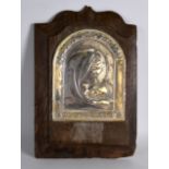 AN UNUSUAL 1920S SILVER PANEL OF A SAINT stamped 925, upon a wooden plaque. Silver 7.5ins x 9ins.
