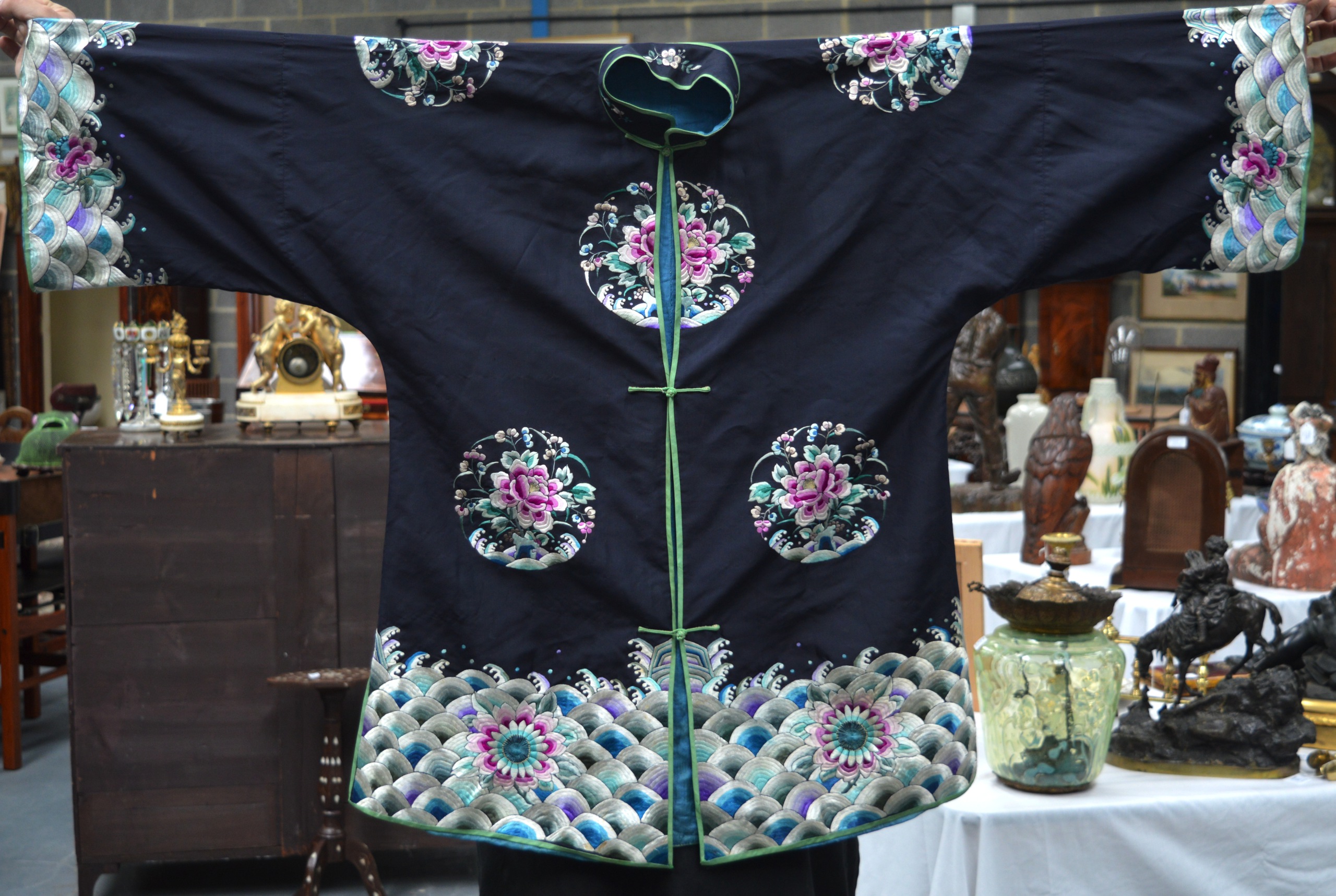 AN EARLY 20TH CENTURY CHINESE BLACK SILKWORK ROBE decorated with panels of flowers, over crashing