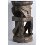 AN AFRICAN CARVED TRIBAL STOOL modelled as a male with arms crossed. 1Ft 1.5ins high.