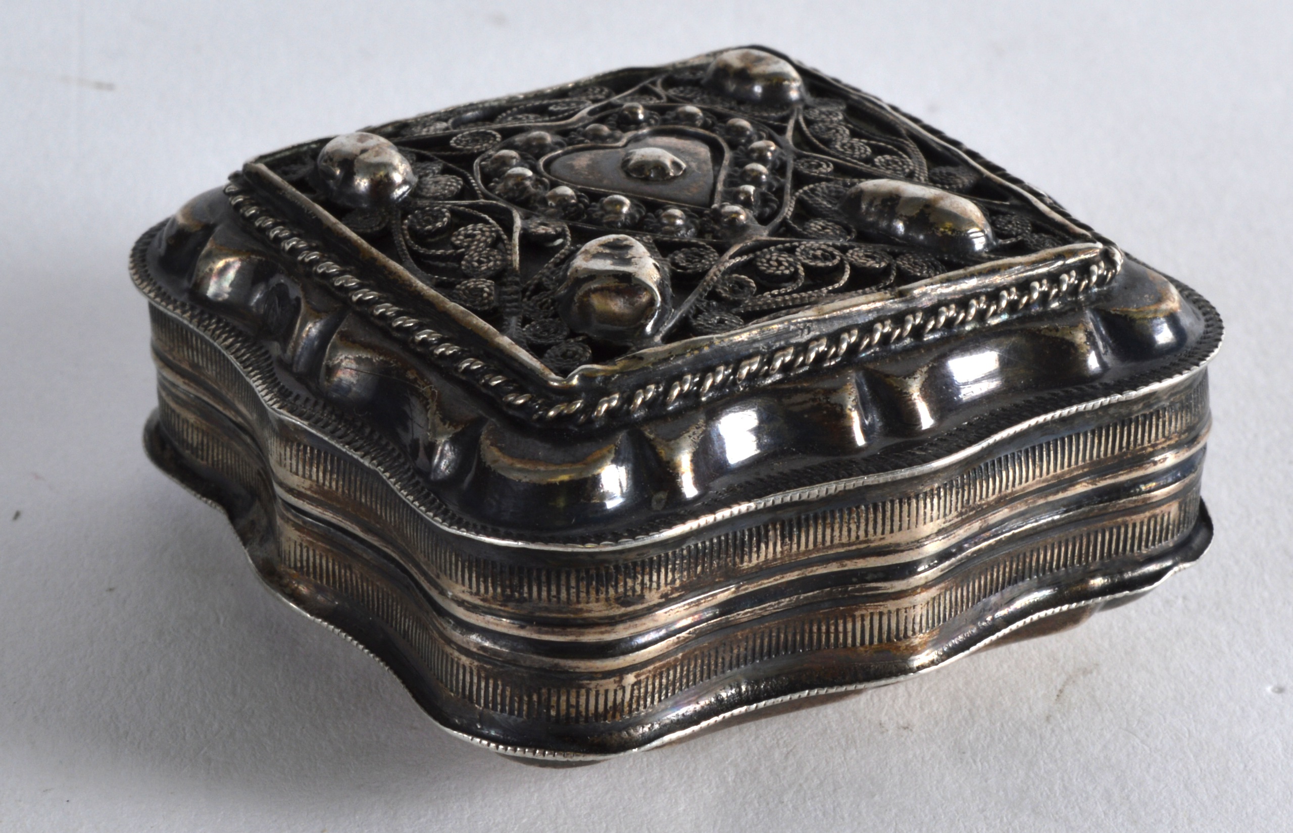 A SMALL CONTINENTAL SILVER SQUARE BOX AND COVER decorated with a heart shaped central motif. 2.25ins