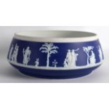 A WEDGWOOD BLUE JASPERWARE FRUIT BOWL decorated with classical figures under trees. 9Ins diameter.