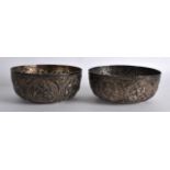 A PAIR OF 19TH CENTURY INDIAN WHITE METAL EMBOSSED BOWLS decorated with buddhistic figures. 406