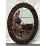A LATE 19TH CENTURY BAVARIAN CARVED BLACK FOREST MIRROR of oval form, decorated with extensive