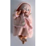 AN EARLY 20TH CENTURY FRENCH BISQUE FIGURE OF A DOLL wearing a pink coat. 7.25ins high.