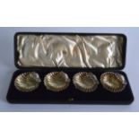 A CASED SET OF VICTORIAN SILVER SALTS in the form of shells. Each 2.25ins wide.