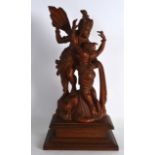 AN EARLY 20TH CENTURY INDIAN CARVED WOOD FIGURE OF A GODDESS modelled beside a clambering female.