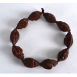 AN EARLY 20TH CENTURY CHINESE CARVED NUT BRACELET each of the ten nuts carved with guanyin. Each nut