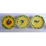 A PAIR OF CONTINENTAL FAIENCE GLAZED YELLOW PLATES and another, decorated with birds. 9Ins diameter.