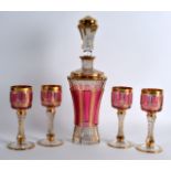 AN EARLY 20TH CENTURY BOHEMIAN RUBY FLASH AND GILT DECANTER with four matching glasses. Decanter