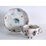 A 19TH CENTURY MEISSEN SIX FOOTED TEACUP AND SAUCER encrusted with flowers and painted with