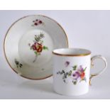 AN 18TH CENTURY COFFEE CAN AND SAUCER painted with flowers under a dentil gilt border.