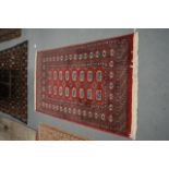 A BEIGE AND RED GROUND RUG decorated with various motifs.
