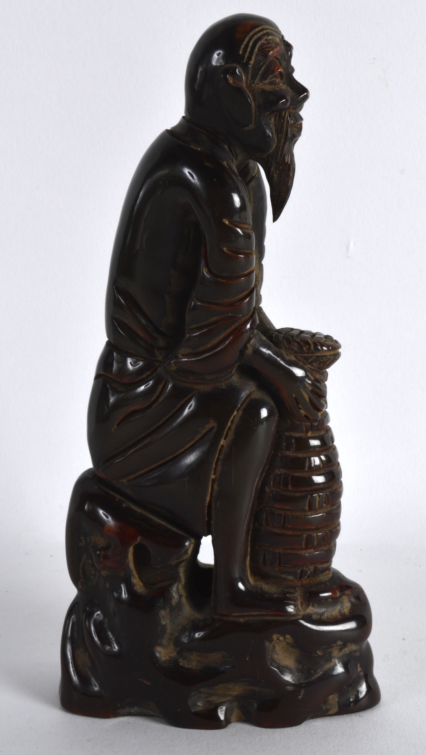 A CHINESE CARVED BUFFALO HORN FIGURE OF A SCHOLAR modelled holding a basket. 6.25ins high.