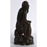 A CHINESE CARVED BUFFALO HORN FIGURE OF A SCHOLAR modelled holding a basket. 6.25ins high.