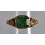 AN 18TH/19TH CENTURY INDIAN YELLOW METAL RING set with an emerald and two white stones.