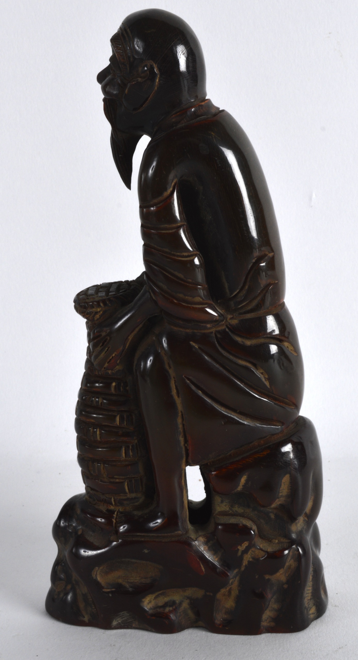 A CHINESE CARVED BUFFALO HORN FIGURE OF A SCHOLAR modelled holding a basket. 6.25ins high. - Image 2 of 2