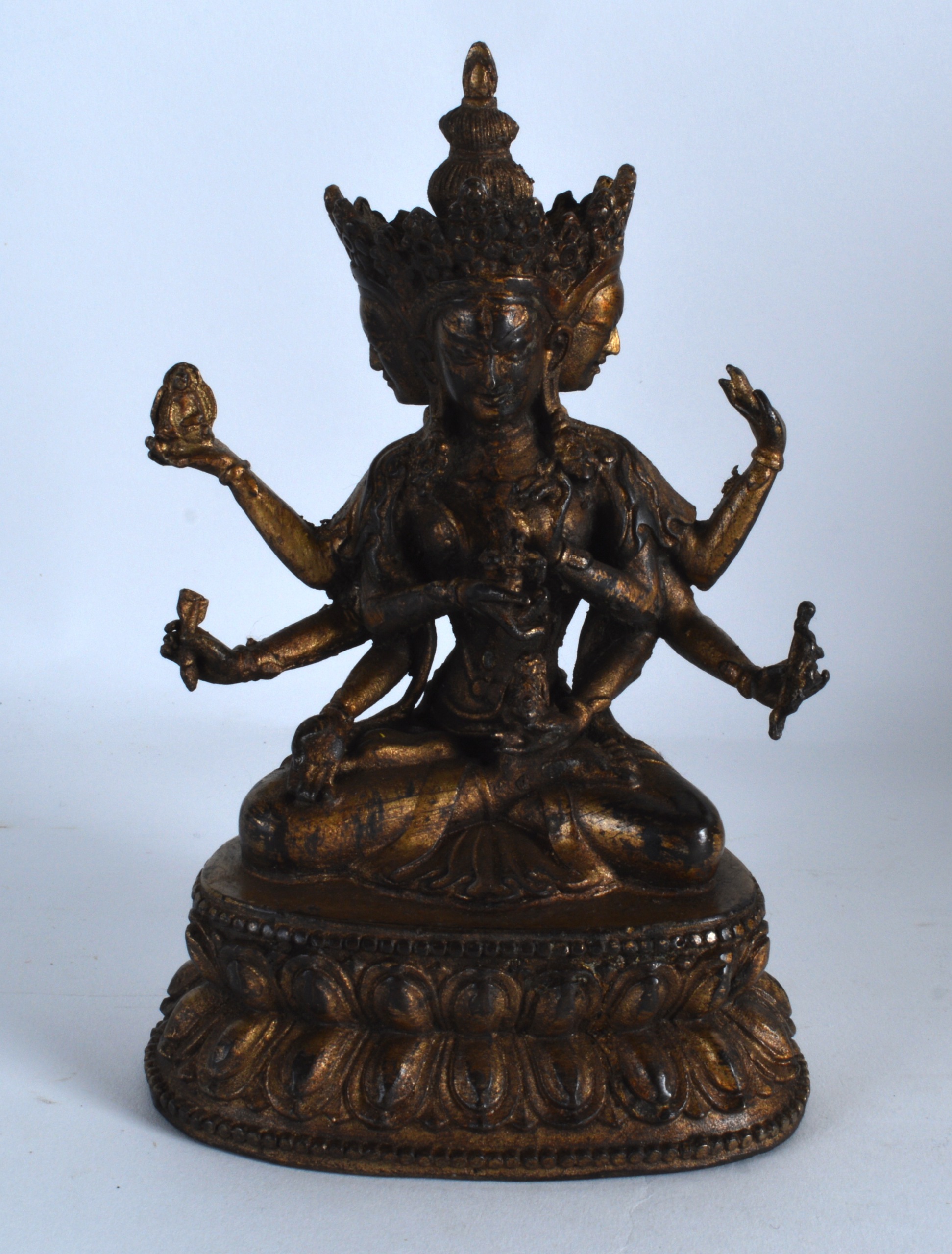 A CHINESE LACQUERED BRONZE FIGURE OF A BUDDHIST GOD modelled upon a triangular base. 7.5ins high.