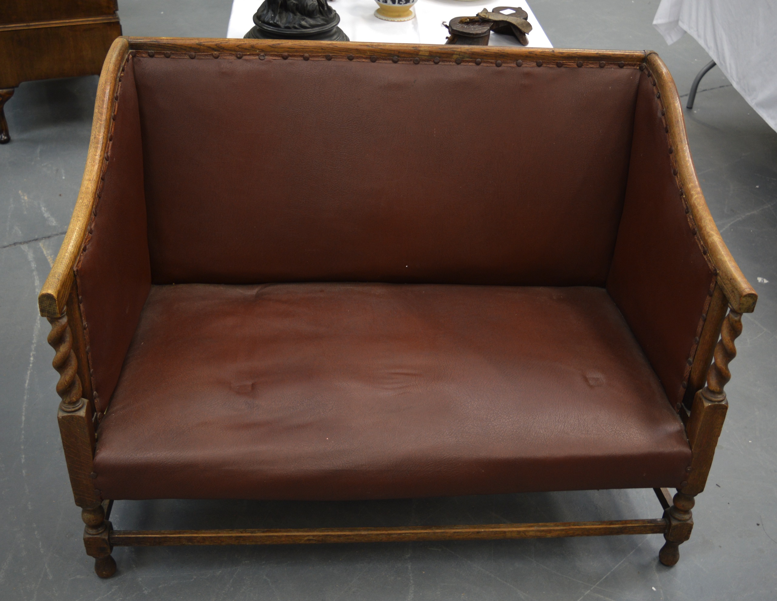 AN ARTS AND CRAFTS TYPE SETTLE with red leather seat & rope twist arm supports. 3 ft 7ins wide.