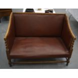 AN ARTS AND CRAFTS TYPE SETTLE with red leather seat & rope twist arm supports. 3 ft 7ins wide.