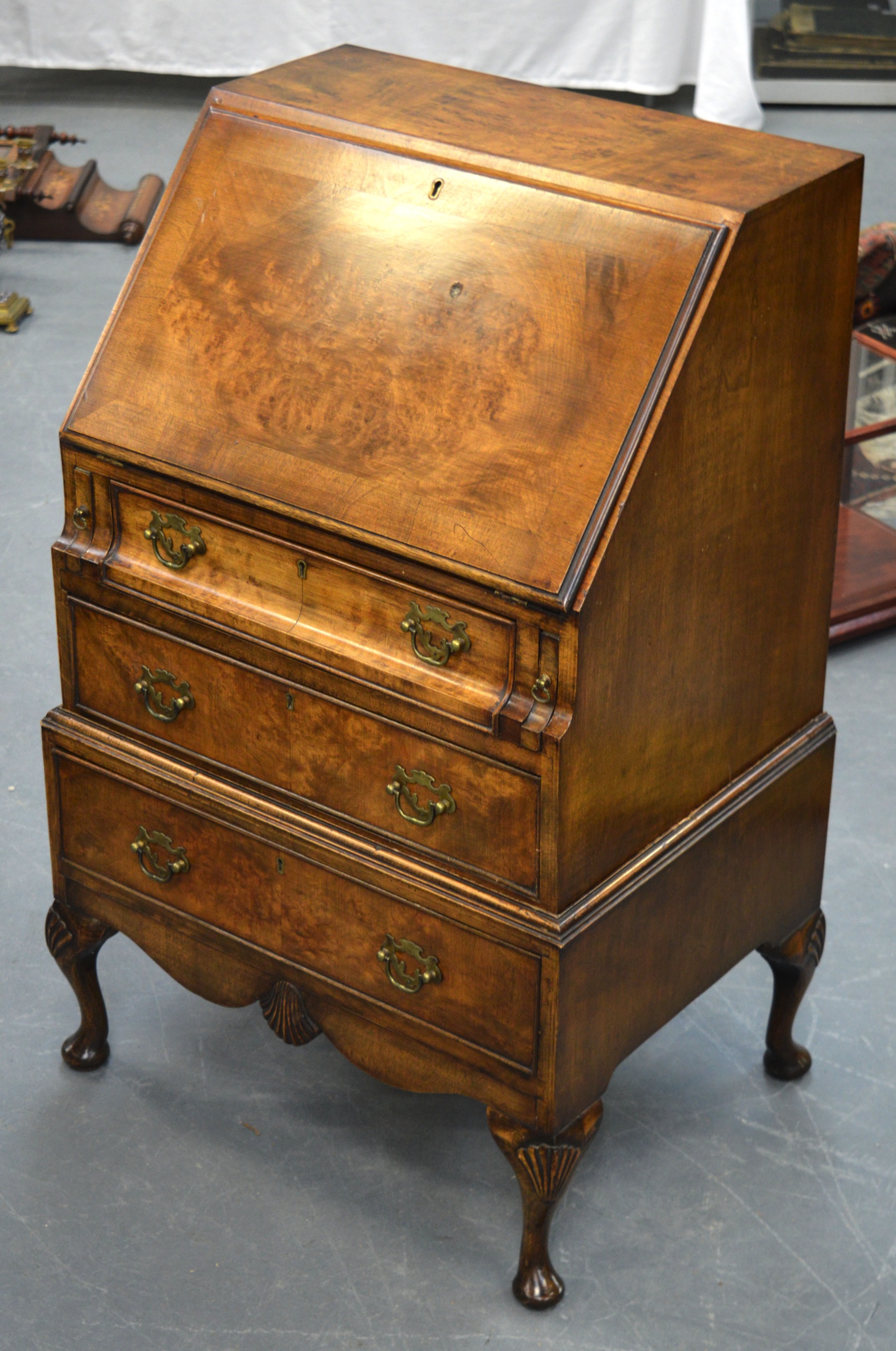 A WALNUT BUREAU ON STAND, three graduated drawers on carved cabriole legs. 3 ft 2ins x 2 ft 1ins.