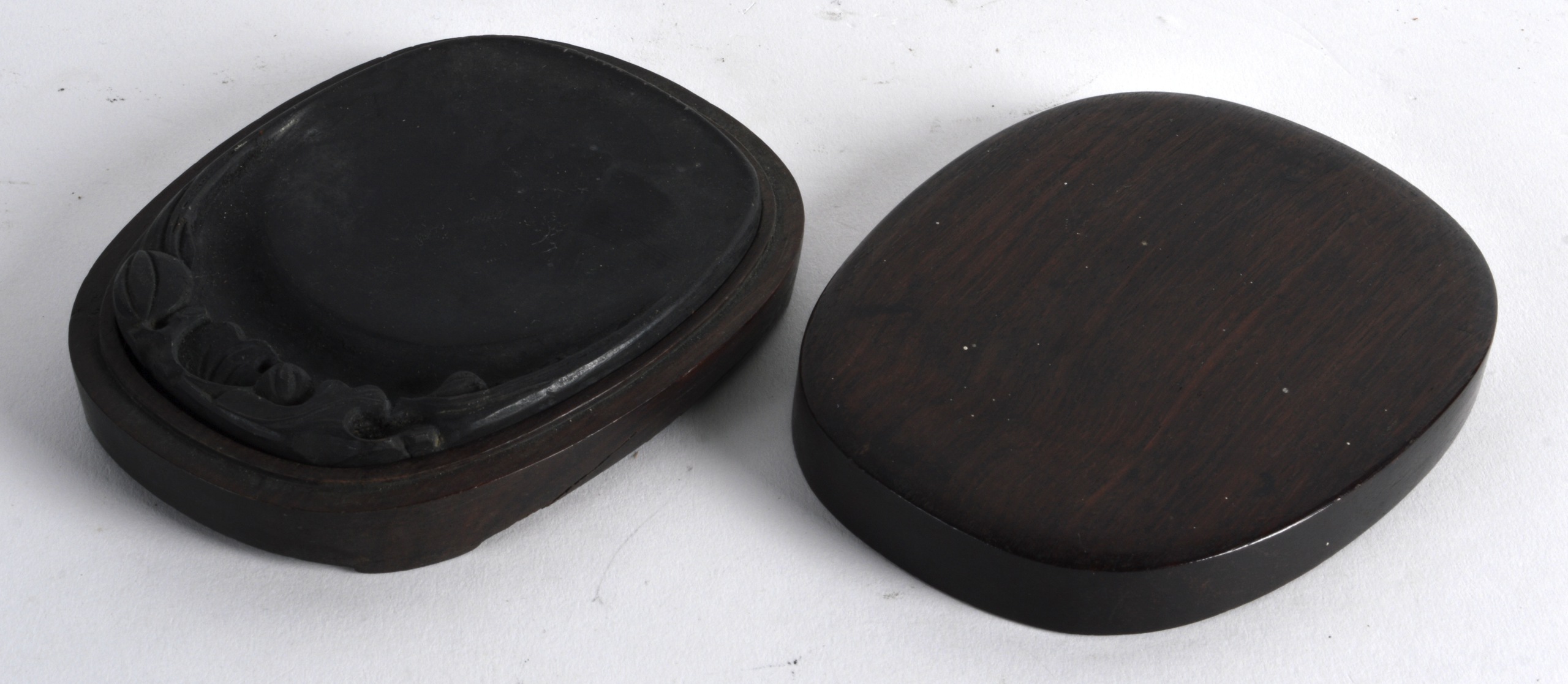 A CHINESE CARVED HARDWOOD OVAL BOX AND COVER with black inkstone. 4.75ins wide.