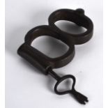 A PAIR OF VICTORIAN IRON HAND CUFFS together with a retro brass spitfire desk stand. (2)