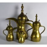 A SET OF FOUR EARLY 20TH CENTURY ARABIC BRASS COFFEE POTS of graduated form. Largest 1ft 11ins high.