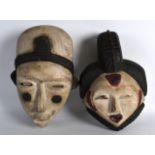 A PAIR OF CARVED AFRICAN MALE AND FEMALE WOODEN MASKS. 11Ins & 10ins long.