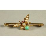 AN EDWARDIAN INSECT TIE PIN, the wings pave set with graduated split seed pearls, ruby cabochon eyes