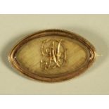 A GEORGE III GOLD MOURNING BROOCH, the eliptical glazed panel enclosing a metal "AD" monogram on a