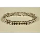 A DIAMOND DOUBLE LINE TENNIS BRACELET, claw set with one hundred brilliant cut diamonds totalling