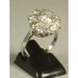 A DIAMOND CLUSTER RING, the central brilliant cut stone of approximately 1.5cts claw set to a border