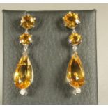 A PAIR OF CITRINE DROP EARRINGS, the facet pear cut stones pendant from two round cut stones and